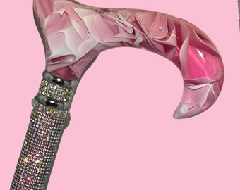 May include: A pink and white marbled walking stick with a crystal-encrusted handle.
