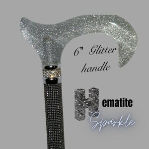 Puede incluir: Un bastón de purpurina plateada con un mango de purpurina de 15 cm y un eje de pedrería negra. El bastón está etiquetado como "Hematite Sparkle".