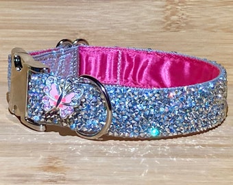 Könnte beinhalten: Ein silbernes Hundehalsband mit einem rosa Schmetterlingsanhänger, besetzt mit klaren Strasssteinen. Das Halsband ist mit rosa Satin gefüttert.