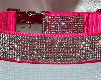 May include: A pink dog collar with a silver buckle and a row of clear rhinestones.