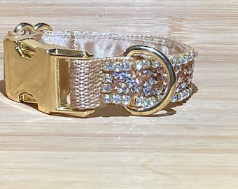 May include: A beige dog collar with a gold buckle and a row of clear and rose gold rhinestones.