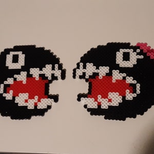 May include: Two black and white pixel art characters with red mouths and white teeth. One character has a pink bow on top of its head.