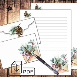 May include: Printable stationery set with a winter theme. The design features envelopes with watercolor illustrations of pine branches, holly, pine cones, and ornaments. The paper has lined writing space.