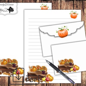 May include: A stationery set featuring a fall harvest theme. The set includes lined paper, an envelope, and a small card, all adorned with illustrations of pumpkins, grapes, and other autumnal elements. A pen rests on the stationery.