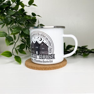 May include: White enamel mug with a black and white graphic of a house with the text "The Haunters of the Witches you couldn't burn Salem, Massachusetts Witch House".