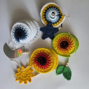 Peut inclure: Ensemble d'ornements crochetés faits à la main, de formes et de couleurs variées. Comprend une spirale blanche, une étoile bleu marine et des motifs circulaires jaunes, oranges et verts. Chaque ornement est relié par une ficelle et des perles en bois.