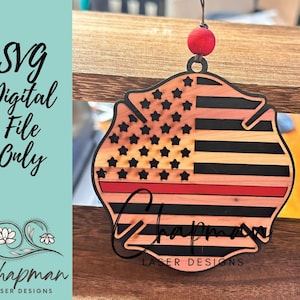 May include: Wooden ornament shaped like a fire fighter's helmet with an American flag design and a red stripe across the middle. The ornament has the text "Chapman Laser Designs" at the bottom.