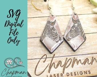May include: A pair of wooden earrings with a diamond shape and a white and black zebra print. The earrings are on a wooden surface with the text "Chapman Laser Designs" printed on it.