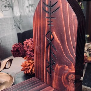 K&ouml;nnte beinhalten: Ein dunkler Holzaltar mit einem geschnitzten Runensymbol. Der Altar ist aus Holz und hat eine dunkelbraune Beize. Das Runensymbol ist in die Vorderseite des Altars geschnitzt und ist ein Symbol f&uuml;r Schutz.