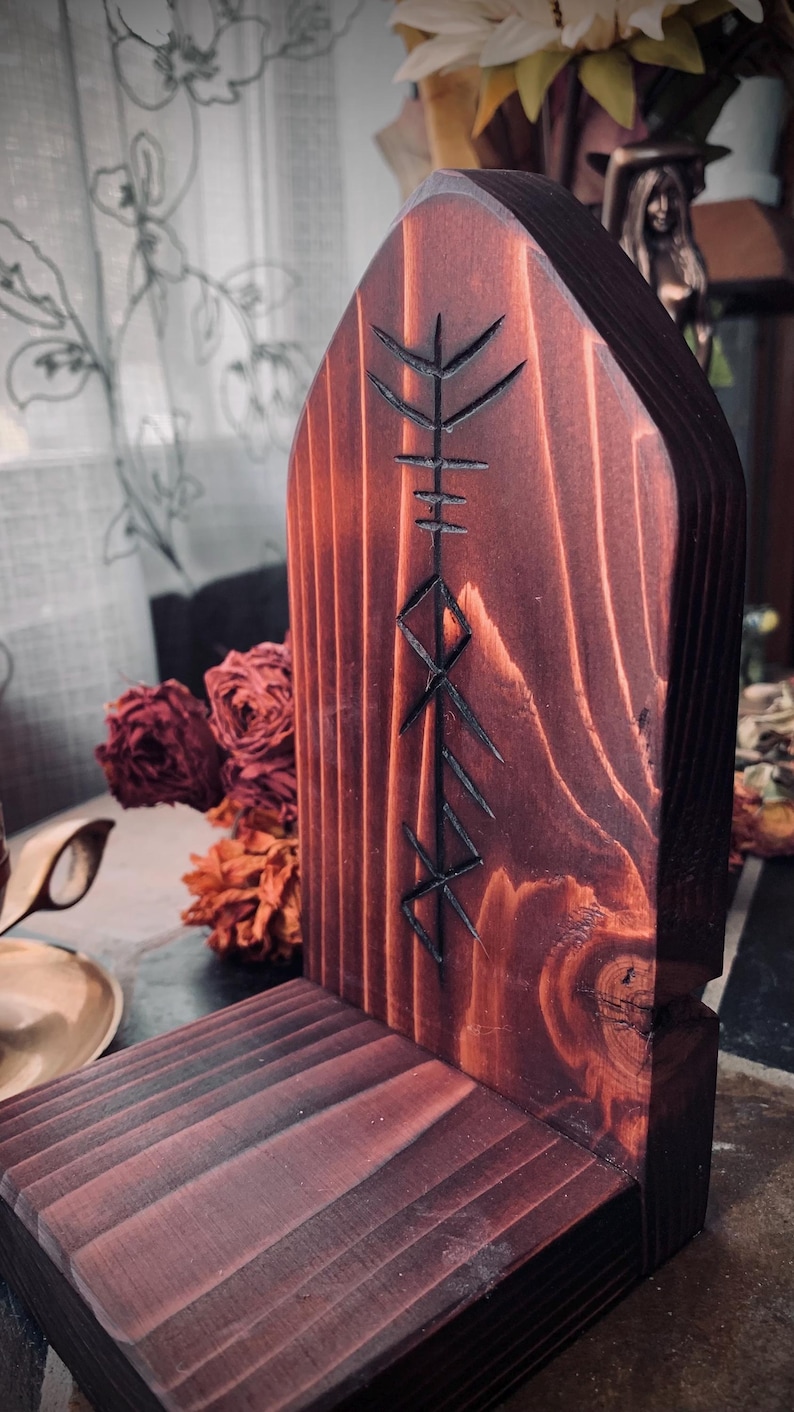 K&ouml;nnte beinhalten: Ein dunkler Holzaltar mit einem geschnitzten Runensymbol. Der Altar ist aus Holz und hat eine dunkelbraune Beize. Das Runensymbol ist in die Vorderseite des Altars geschnitzt und ist ein Symbol f&uuml;r Schutz.