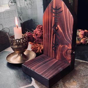 K&ouml;nnte beinhalten: Ein dunkelbrauner Holzaltar mit einem geschnitzten Runensymbol. Der Altar hat eine Ablagefl&auml;che zum Aufstellen von Kerzen oder anderen Gegenst&auml;nden. Der Altar steht auf einem gefliesten Boden.