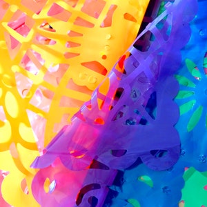 May include: Colorful paper cutouts in shades of yellow, orange, pink, purple, blue, and green. The cutouts are layered on top of each other, creating a vibrant and festive display.