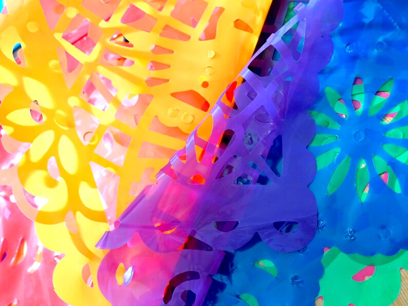 May include: Colorful paper cutouts in shades of yellow, orange, pink, purple, blue, and green. The cutouts are layered on top of each other, creating a vibrant and festive display.