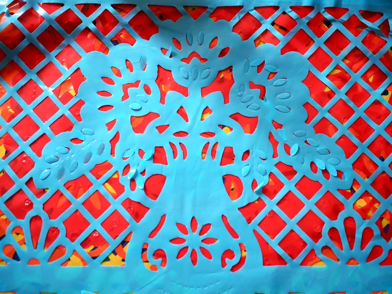 May include: A blue paper cutout of a traditional Mexican design with intricate floral patterns. The cutout is layered over a red and yellow paper background.