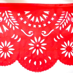 May include: Red paper banner with white cut-out designs. The banner features a scalloped edge and intricate patterns including flowers, leaves, and swirls.