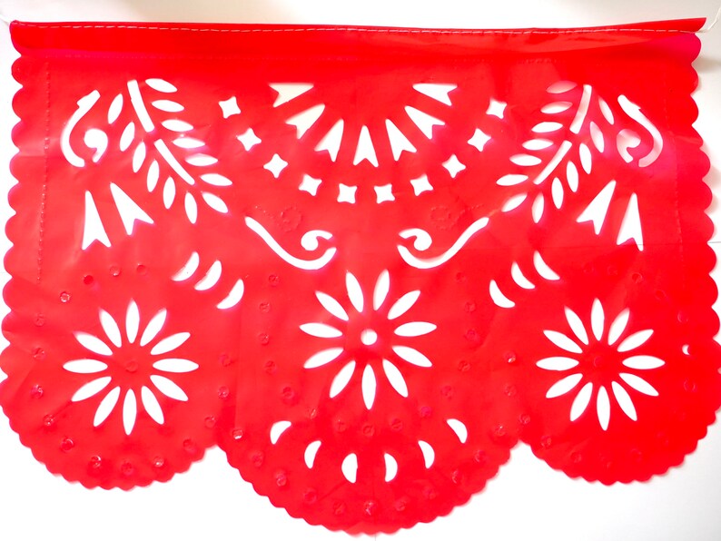 May include: Red paper banner with white cut-out designs. The banner features a scalloped edge and intricate patterns including flowers, leaves, and swirls.