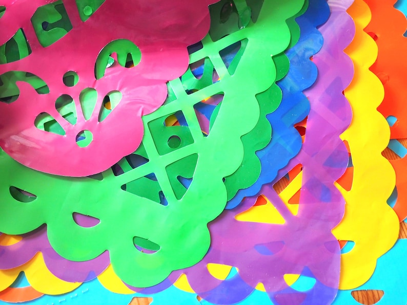 May include: A stack of colorful paper cutouts with intricate designs. The cutouts are layered in a rainbow pattern, starting with pink at the top and ending with blue at the bottom.