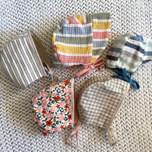 May include: Five different baby bonnets in various patterns and colors. The bonnets are made of soft, breathable fabric and are perfect for keeping a baby's head warm and protected from the sun.