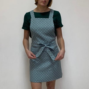 May include: A blue and white polka dot apron with a tie at the waist and a pocket on the front.