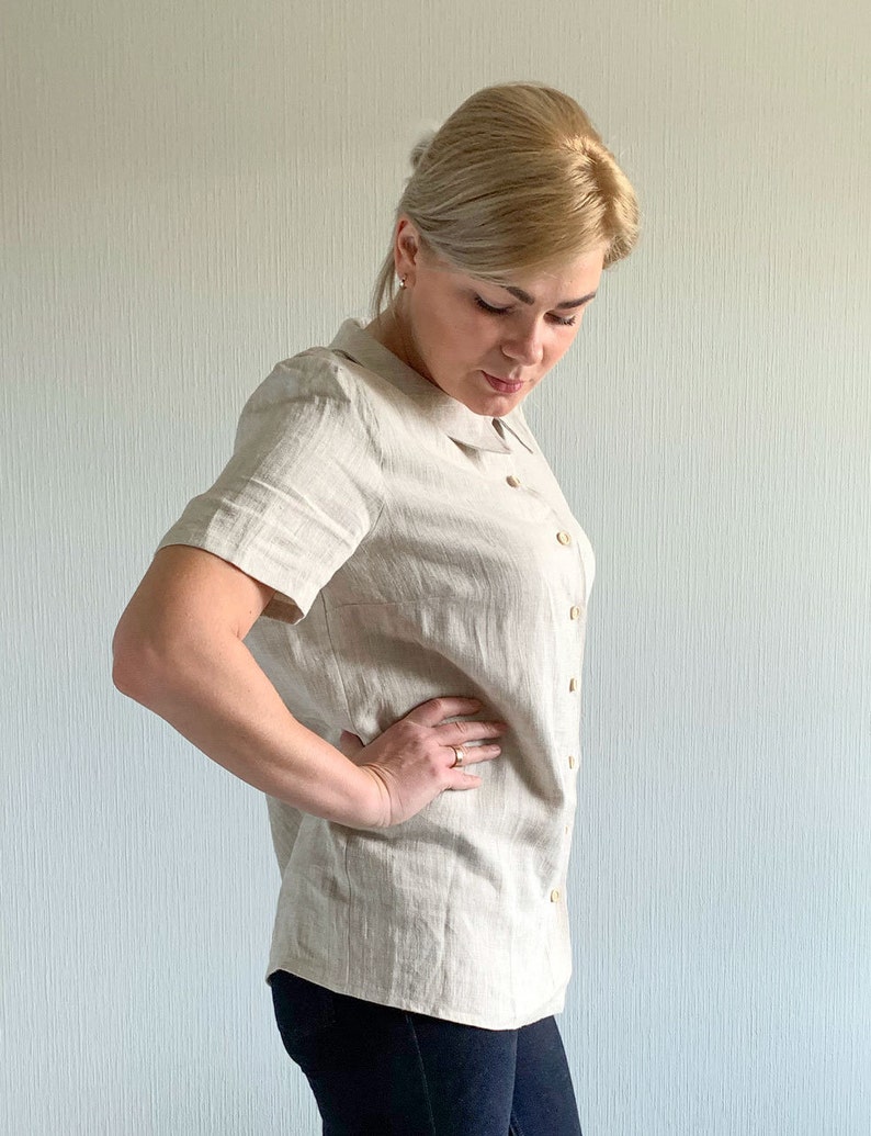 May include: A beige linen shirt with a collar and short sleeves. The shirt has a button-up front and is made of a lightweight fabric.