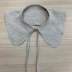 May include: A grey linen collar with a tie fastening. The collar is large and has a rounded shape.