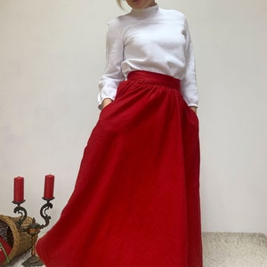 May include: A red maxi skirt with a high waist and pockets. The skirt is made of a soft, flowing fabric.