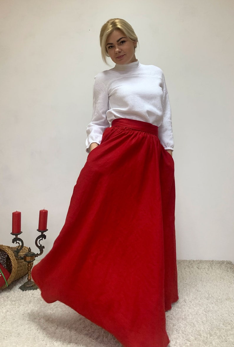 May include: A red maxi skirt with a high waist and pockets. The skirt is made of a soft, flowing fabric.