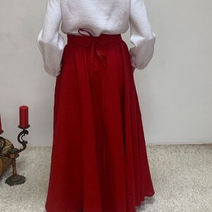 May include: A long, red skirt with a tie at the waist. The skirt is made of a soft, flowing fabric.
