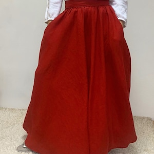 May include: A long, red, flowing skirt with a wide waistband. The skirt is made of a soft, linen fabric.