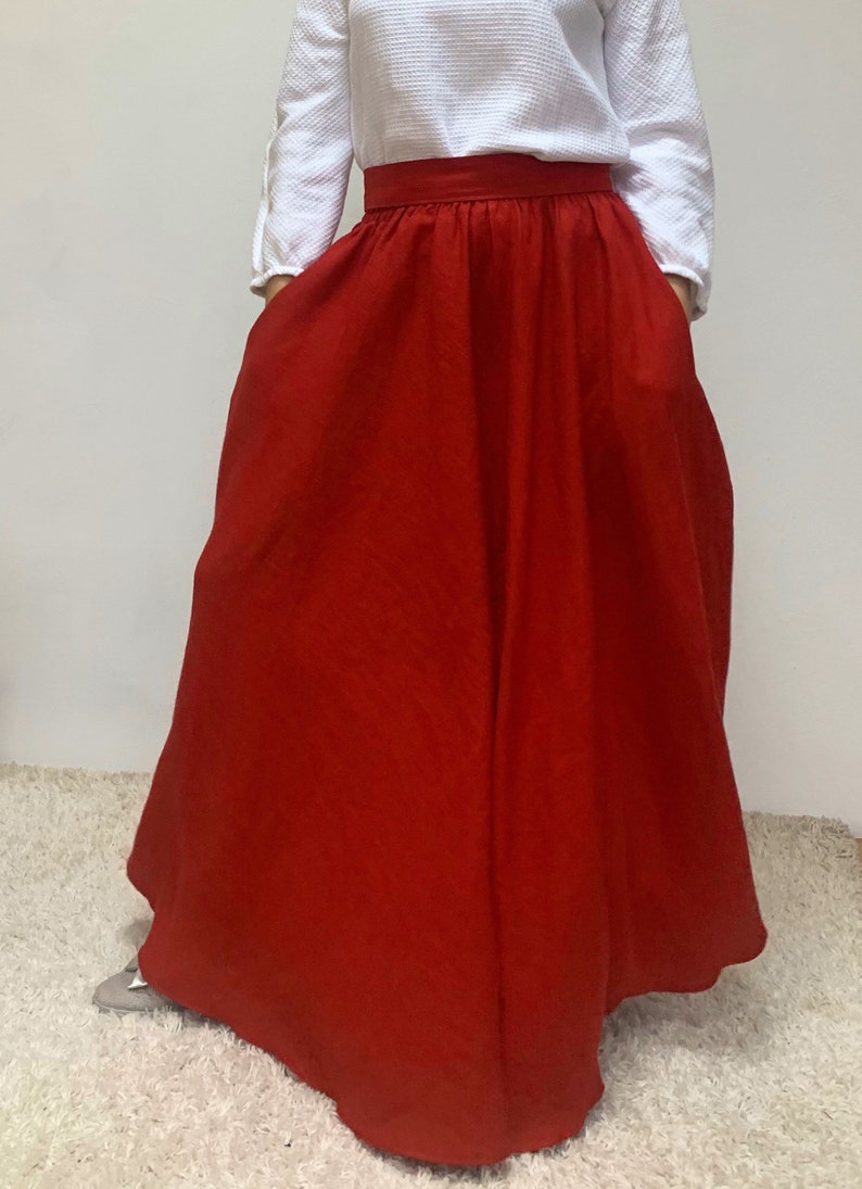 May include: A long, red, flowing skirt with a wide waistband. The skirt is made of a soft, linen fabric.