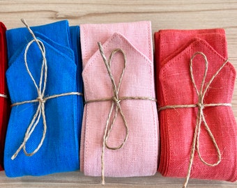 Könnte beinhalten: Vier Stoffbandrollen, die mit Schnur gebunden sind. Die Rollen sind blau, rosa, rot und burgunderrot.