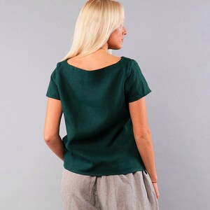 May include: A dark green linen top with a square neckline and short sleeves. The top is loose fitting and has a relaxed silhouette.