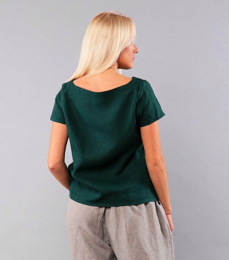 May include: A dark green linen top with a square neckline and short sleeves. The top is loose fitting and has a relaxed silhouette.