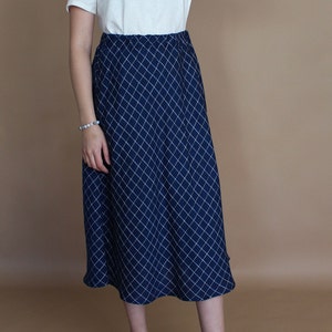 May include: A navy blue skirt with a white diamond pattern. The skirt is knee-length and has a fitted waist.
