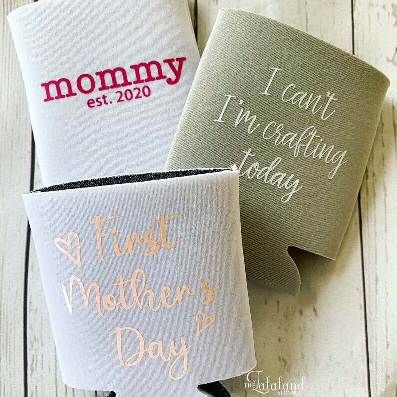 Puede incluir: Tres aislantes de bebidas de espuma blanca con diferentes textos impresos. El primer aislante tiene el texto "mommy est. 2020" impreso en rojo. El segundo aislante tiene el texto "I can't I'm crafting today" impreso en blanco. El tercer aislante tiene el texto "♡First Mother's Day♡" impreso en oro rosa.