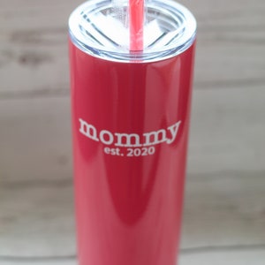 Puede incluir: Un vaso de acero inoxidable rosa con tapa blanca y una pajita blanca. El vaso tiene el texto "mommy est. 2020" impreso en el lateral.