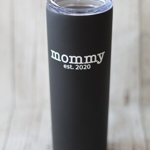 Puede incluir: Un vaso de acero inoxidable negro con una tapa transparente. El vaso tiene el texto "mommy est. 2020" impreso en blanco.