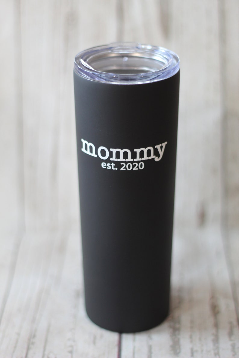 Puede incluir: Un vaso de acero inoxidable negro con una tapa transparente. El vaso tiene el texto "mommy est. 2020" impreso en blanco.