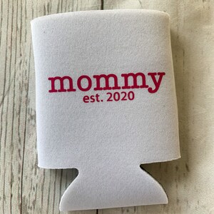 Puede incluir: Enfriador de latas de espuma blanca con el texto "mommy est. 2020" en rojo.