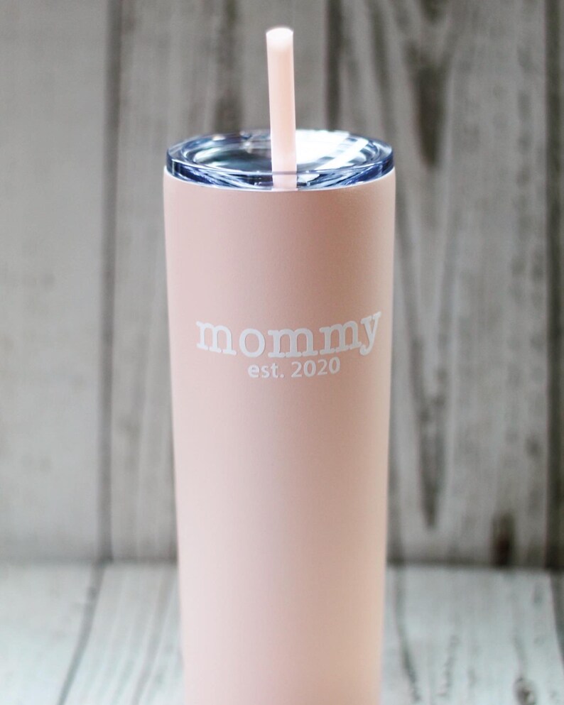 Puede incluir: Un vaso de acero inoxidable rosa con tapa transparente y una pajita. El vaso tiene el texto "mommy est. 2020" impreso en &eacute;l.