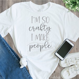 May include: White t-shirt with the text "I'm so crafty. I make people" in gray lettering.