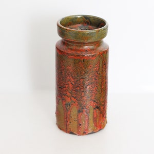 May include: A tall, cylindrical ceramic vase with a textured, drip-like glaze in shades of orange and green.