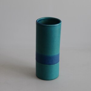 May include: A teal blue ceramic vase with a single blue band around the middle.