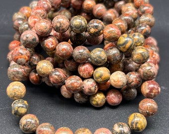 Puede incluir: Un conjunto de pulseras hechas con cuentas de jaspe rojo, marrón y negro. Las cuentas tienen un patrón de remolino.