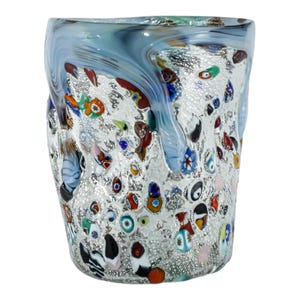 May include: A cylindrical glass vase featuring a textured, silver-flecked surface embedded with numerous multicoloured millefiori glass beads. The upper rim is accented with swirling streaks of translucent blue and grey glass.