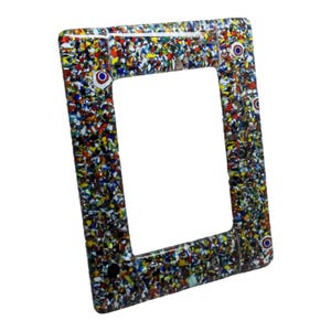 May include: A rectangular light switch plate with a mosaic design. The plate is made of a clear material embedded with colourful pieces of glass in shades of red, blue, yellow, and green. The plate has a rectangular opening and screw holes.