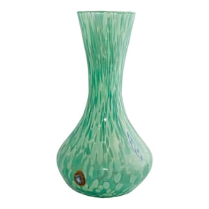May include: A green glass vase with a rounded base and a narrow neck. The vase features a speckled design of lighter green and white, with a few darker brown marks near the base. The vase is empty and set against a white backdrop.