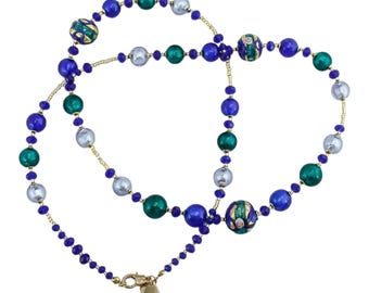 May include: A multi-strand necklace featuring a mix of blue, green, and silver beads. The necklace has gold-colored chain and a heart-shaped charm. The beads vary in size and are interspersed with smaller, darker blue beads.