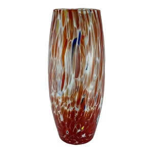 Puede incluir: Un jarrón de vidrio alto y ovalado con un diseño moteado. El jarrón presenta una base de color rojo intenso, que transiciona a tonos más claros de marrón y blanco, con toques de azul y amarillo. Un elemento decorativo para el hogar.