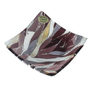 Op de afbeelding: Vierkante glazen schaal met een mozaïekontwerp in paars, wit en goud. De schaal heeft een label met de tekst "Murano certificate Glass".